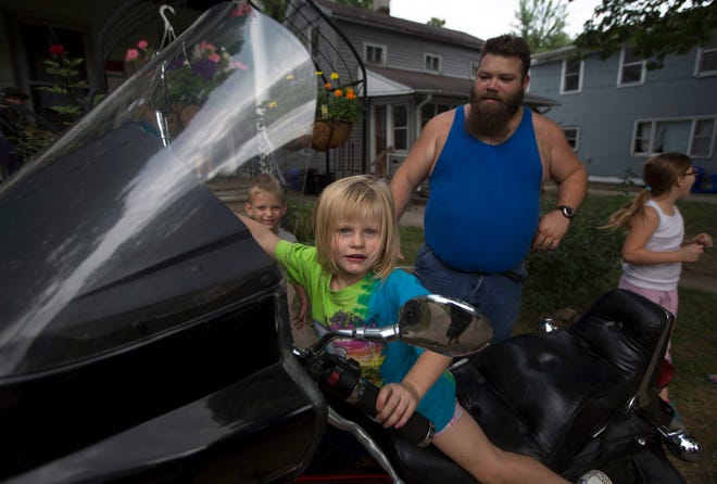 Clifford Stuthers (right) allows his foster daughter Paige Conway, 4, to start the engine of his motorcycle Wednesday, Aug. 5, 2015, on Benton Street in the Jackson Oaks neighborhood. SUNNY STRADER/RRSTAR.COM