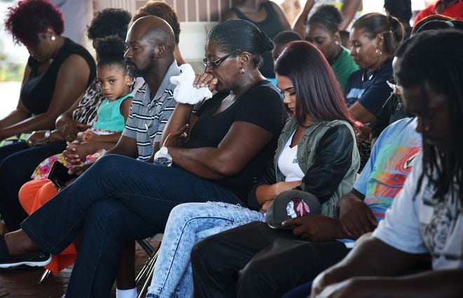 In this Journal Star file photo, family members bow their heads during a prayer at a "stand down for peace" event organized by Peoria Community Against Violence in response to the killing of Quenton D. Lowe.