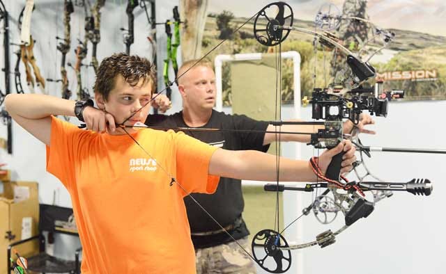 Aidan Robertson and his father Jason Posey practice archery Tuesday inside Neuse Sport Shop. The duo recently won a state archery competition.