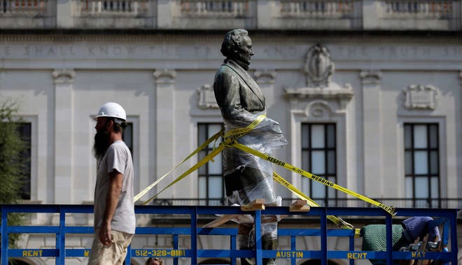 A statue of Confederate President Jefferson Davis is moved from it's location in front of the school's main tower the University of Texas campus, Sunday, Aug. 30, 2015, in Austin, Texas. The Davis statue, which has been targeted by vandals and had come under increasing criticism, will be moved and placed in the school's Dolph Briscoe Center for American History as part of an educational display. (AP Photo/Eric Gay)