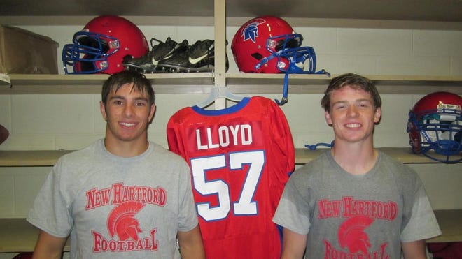 New Hartford senior football players Kyle Kuty, left, and Ryan Murray, close friends of the late Spartan lineman John Lloyd, stand in the Perry Junior High equipment room alongside Lloyd's jersey. The Spartans, who host Jamesville-DeWitt in Friday night's opener, are dedicating this season to Lloyd, who died Jan. 22, 2014, after a long battle with Hodgkin's lymphoma.