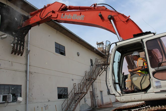 NAS Jax Commanding Officer Capt. Howard Wanamaker uses an excavator to tear down part of Hangar 113, following a ceremony Aug. 24. Additionally, Hangars 114, and 115 are also being torn down due to the age and non-use of the facilities.
