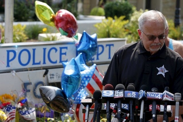 George Filenko of the Lake County Major Crimes Task Force holds a news conference at a vigil for slain Fox Lake Police Lieutenant Charles Joseph Gliniewicz in Fox Lake, Illinois, United States, September 2, 2015. Authorities in northern Illinois expanded their search for three suspects in the fatal shooting of a 30-year police officer as local schools were closed on Wednesday and vigils for the officer were planned. REUTERS/Jim Young  
 A woman places flowers at a vigil for slain Fox Lake Police Lieutenant Charles Joseph Gliniewicz in Fox Lake, Illinois, United States, September 2, 2015. Authorities in northern Illinois expanded their search for three suspects in the fatal shooting of a 30-year police officer as local schools were closed on Wednesday and vigils for the officer were planned. REUTERS/Jim Young