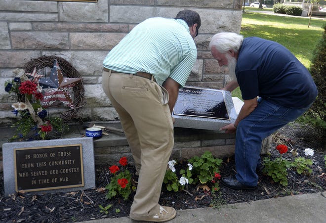 Jerry Fisher, right, gets some help from Aaron Grivna Wednesday morning placing a plaque honoring local Tuskegee Airmen at the World War II memorial along Third Street in Beaver. Both are from Brighton Township.