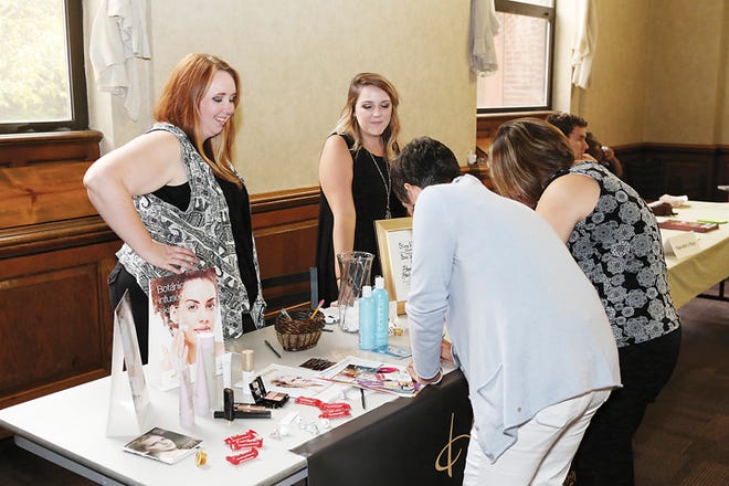 Amanda Harris, left, of Addison and Sarah Ladd of Manitou Beach register students to win free hair care 
products from Headliners Hair Studio on Thursday during the “Taste of Adrian” event at Siena Heights 
University.