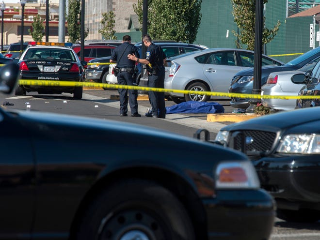 Police officers stand near the body of a victim killed in a shooting at Sacramento City College, Thursday, Sept. 3, 2015, in Sacramento, Calif. The shooting occurred in a parking lot near the baseball field on the college campus.