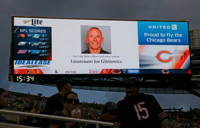 The late Fox Lake Police officer Lt. Charles Joseph Gliniewicz is displayed on a scoreboard during the first half of an NFL preseason football game between the Chicago Bears and the Cleveland Browns, Thursday, Sept. 3, 2015, in Chicago. Gliniewicz, a 30-year police veteran, was shot Tuesday in the village of Fox Lake. Authorities broadened the hunt Wednesday for three suspects wanted in the fatal shooting of the popular Illinois police officer, even as they acknowledged that they had no indication the men were still in the area where the slaying happened. (AP Photo/Nam Y. Huh)
