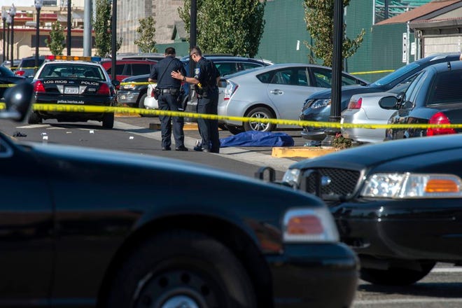 Police officers stand near the body of a victim killed in a shooting at Sacramento City College, Thursday, Sept. 3, 2015, in Sacramento, Calif. The shooting occurred in a parking lot near the baseball field on the college campus. (Renée C. Byer/The Sacramento Bee via AP)