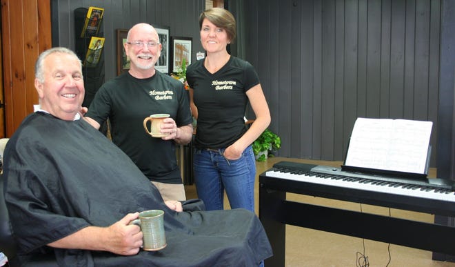 Barbers Steve Landry and Tina Gemborys pose in their new barbershop, Hometown Barbers, with customer John Cormier of Gardner. Jay Gearan