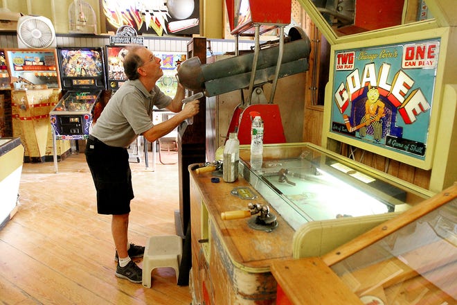 John Bateman, the owner of the arcade at Spring Lake Beach, adjusts the gunsight on "Sky Fighter," a game from the late 1930s. On the right is "Goalee," a hockey game from the 1940s. The Providence Journal/Glenn Osmundson