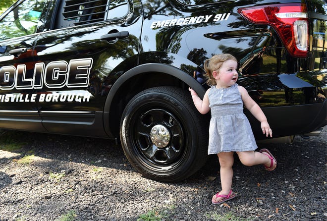 Alivia Brindley, 2, of Morrisville, hangs on a police car during the annual Labor Day Mayor's Picnic at Williamson Park in Morrisville on Labor Day, Monday, September 7, 2015.