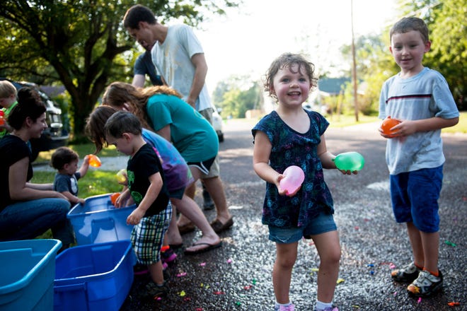 Arianna Boone, 4, second from right, plays a game with water balloons Sunday with other children during a neighborhood block party organized by Leslie Rigdon in the 200 block of West Forest Avenue.