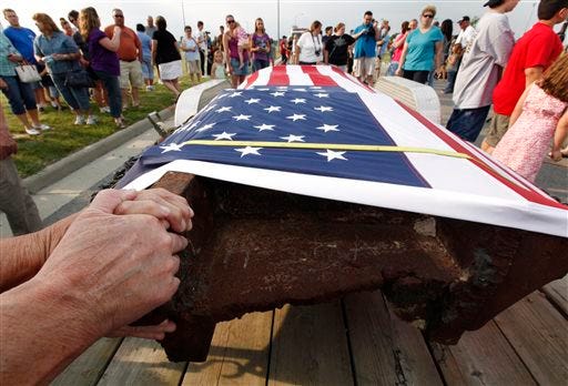 In this June 17, 2011, file photo, people touch a 12-foot steel beam from the World Trade Center during the beam's arrival from New York City in Wauseon, Ohio. Pieces of steel from the twin towers have been parceled out to all 50 states and eight countries for memorials and museum exhibits and were used in the construction of the U.S. Navy ship USS New York. Of 2,200 pieces of steel preserved in an airplane hangar in New York City, there are fewer than 30 left. (AP Photo/Paul Sancya, File)