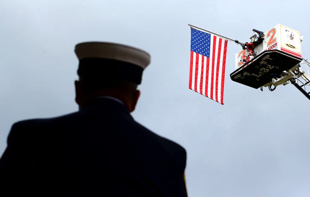 A flag hangs from the top of a Hugo Fire Department ladder truck on Friday at the Sept. 11 Memorial Service at Pearson Park in Kinston.