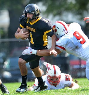 Framingham State quarterback Matt Silva is pursued by Cortland State tacklers Matt Ambrose (9) and Troy Beddoe during Saturday's game at Bowditch Field.
