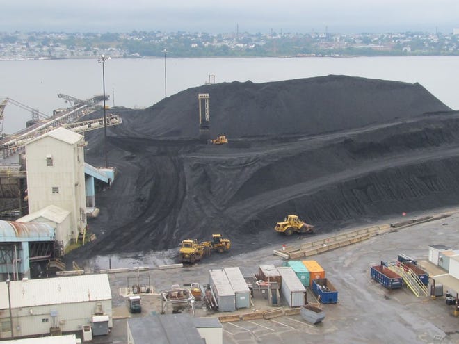 Brayton Point bulldozers push and load pile of some 430 tons of coal delivered by ship and barge into conveyor where it will be loaded into pulverizers and boilers.