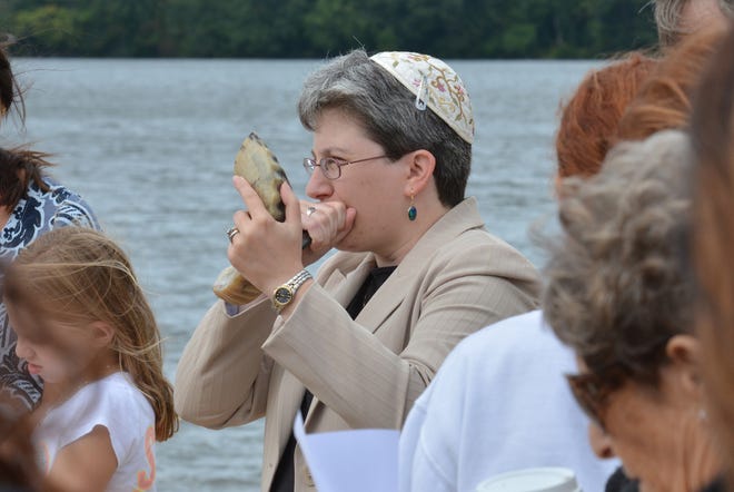 WESTBORO - Rabbi Rachel Gurevitz of B'nai Shalom blows the shofar as she leads a Tashlich ceremony at Lake Chauncy on the first day of Rosh Hashanah, celebrating the Jewish new year. Tashlich involves using bread to symbolically cast sins into the water in order to enter the new year with a pure spirit. Photo/Chris Christo