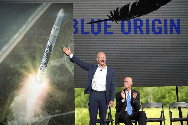 Amazon CEO Jeff Bezos, left, unveils the new Blue Origin rocket, as Florida Gov. Rick Scott, right, applauds during a news conference at the Cape Canaveral Air Force Station in Cape Canaveral, Fla., Tuesday, Sept. 15, 2015. Bezos announced a $200 million investment to build the rockets and capsules in the state and launch them using the historic Launch Complex 36. (AP Photo/Phelan M. Ebenhack)