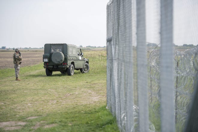 A Hungarian military cartographer stands next to a vehicle parked at the temporary border fence between Hungary and Serbia near the Serbian and the Romanian borders,, 187 kms southeast of Budapest, Hungary, Wednesday. The Associated Press
