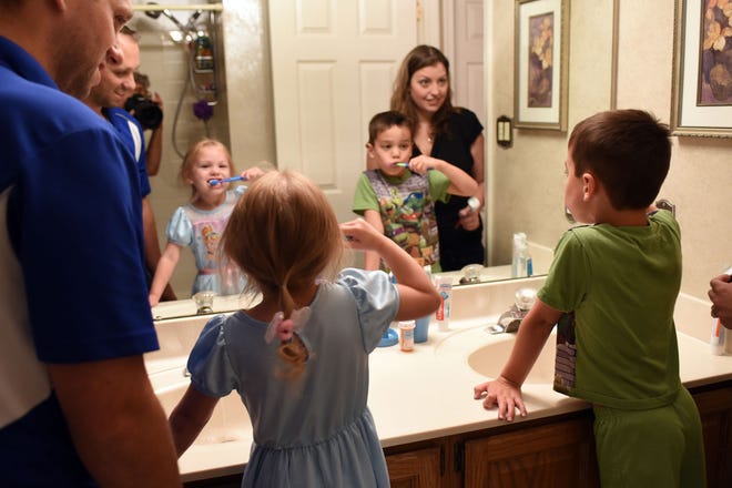 Brian and Jamie Sherfesee help kids Julia and Anthony with tooth brushing before bed. Photo by William Johnson