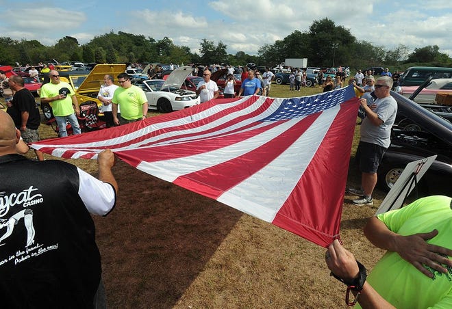 Auto buffs hold the flag as the national anthem is sung at the beginning of the auto show during the Spirit of Somerset Family Fun Day.