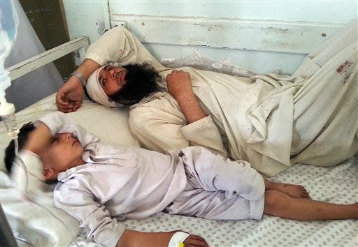 A wounded Afghan man and a child lie on a bed after they were wounded in an explosion in Kunar province, Afghanistan, Sunday, Sept. 20, 2015. An Afghan official says several people, including two police officers, were wounded in a suicide attack near Kandahar on Sunday. More than a dozen civilians were wounded after a bomb hidden near an electric station exploded in eastern Kunar province, said Gen. Abdul Habib Sayedkhaili, the provincial police chief. (AP Photo)