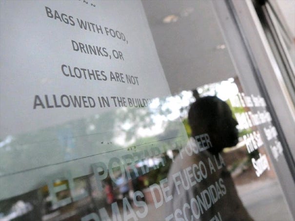 A man walks past a sign at the entrance of the main branch of The New Hanover County Library in downtown Wilmington. The sign is about a policy banning bags with clothes inside the library.