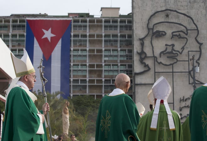 Pope Francis holds his pastoral staff as he arrives to celebrate Mass at Revolution Plaza in Havana, Cuba, Sunday, as a sculpture of revolutionary hero Ernesto "Che" Guevara and a Cuban flag decorate a nearby government building. The Associated Press