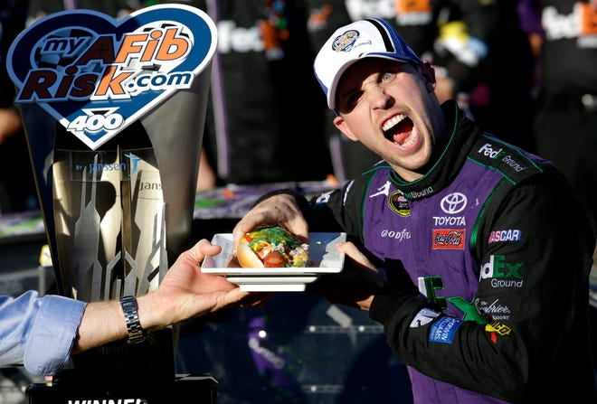 Denny Hamlin prepares to eat a Chicago-style hot dog in Victory Lane after winning the Sprint Cup race at Chicagoland Speedway on Sunday. The Associated Press