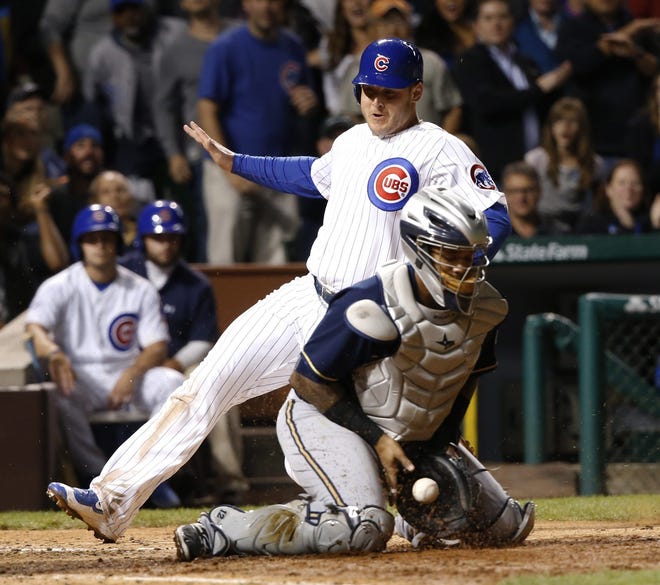 Chicago Cubs' Anthony Rizzo, left, scores past Milwaukee Brewers catcher Martin Maldonado, on a hit by Miguel Montero, during the fifth inning of a baseball game, Monday, Sept. 21, 2015, in Chicago. (AP Photo/Charles Rex Arbogast)
