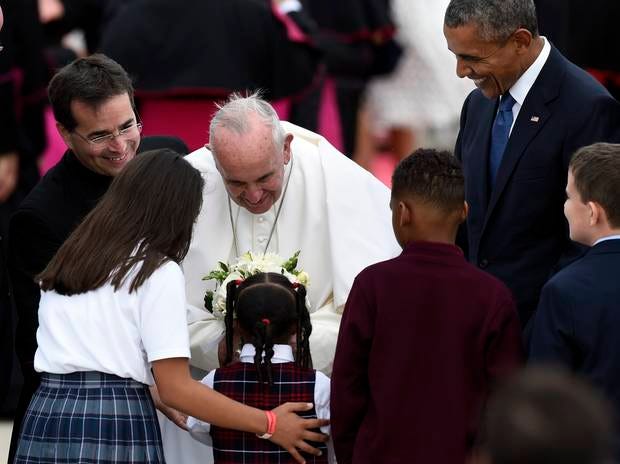 Pope Francis greets children and receives flowers as he is escorted by President Barack Obama after arriving at Andrews Air Force Base, Md., Tuesday, Sept. 22, 2015. The Pope is spending three days in Washington before heading to New York and Philadelphia. This is the Pope's first visit to the United States. (AP Photo/Susan Walsh)
