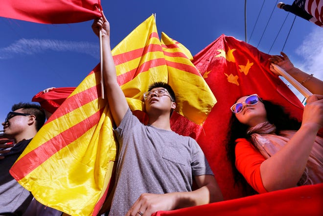 Frank Shen, left, and Chen Xiaohong holds Chinese flags to welcome Chinese President Xi Jinping as other protesters try to cover their flags with 1970's-era South Vietnam flags before a visit to Lincoln High School by the president Wednesday, Sept. 23, 2015, in Tacoma, Wash. Xi is on the second of a three-day trip to Seattle before traveling to Washington, for a White House state dinner on Friday. (AP Photo/Elaine Thompson)