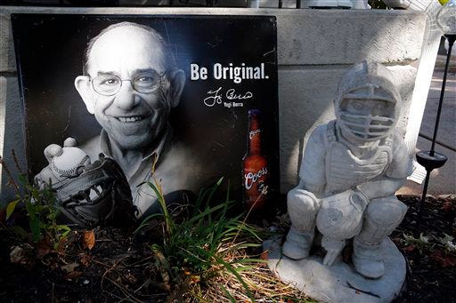Photos and baseball-themed lawn ornaments sit outside the boyhood home of Hall of Fame catcher Yogi Berra Wednesday in St. Louis. Berra, who grew up in St. Louis, played in more World Series games than any other major leaguer and was a three-time American League Most Valuable Player, died Tuesday of natural causes. He was 90. (AP Photo)
