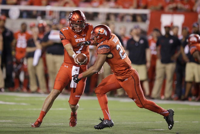 Utah quarterback Travis Wilson (7) hands the ball off to Utah running back Devontae Booker, right, in the second half during an NCAA college football game against Michigan, Thursday, Sept. 3, 2015, in Salt Lake City. (AP Photo/Rick Bowmer)