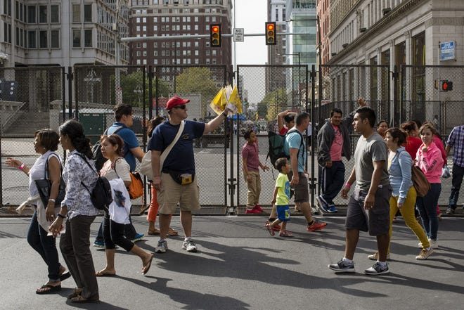 Pedestrians walk past a fenced off portion of Arch Street during the final day of the World Meeting of Families, on Friday afternoon, in Philadelphia.