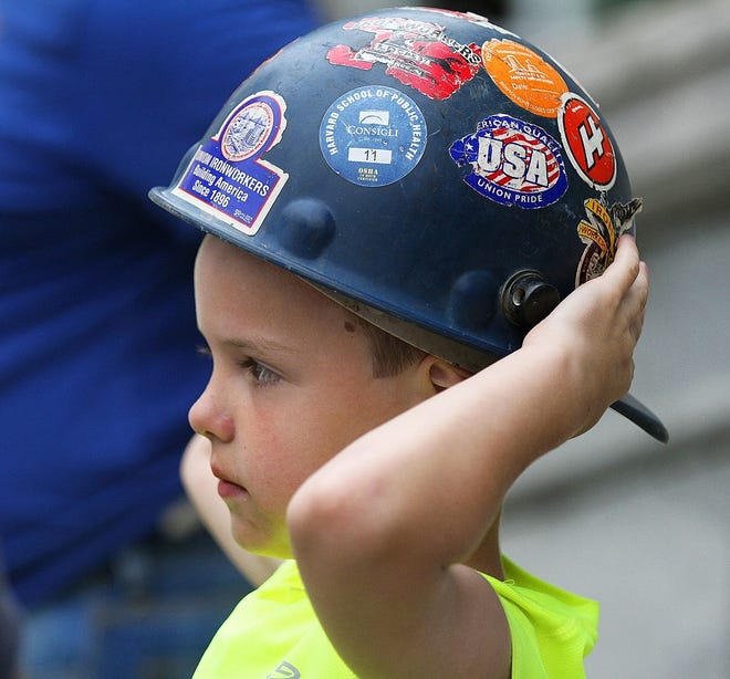 Gracin Tanguay, 6, of Lincoln, tries on his father's hard hat, during a rally in July at Providence City Hall. THE PROVIDENCE JOURNAL/GLENN OSMUNDSON