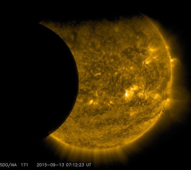 This Sept. 13, 2015 image provided by NASA shows the moon, left, and the Earth, top, transiting the sun together, seen from the Solar Dynamics Observatory. The edge of Earth appears fuzzy because the atmosphere blocks different amounts of light at different altitudes. This image was taken in extreme ultraviolet wavelengths, invisible to human eyes, but here colorized in gold. A total lunar eclipse will share the stage with a so-called supermoon Sunday evening, Sept. 27, 2015 as seen from the United States. That combination hasn't been seen since 1982 and won't happen again until 2033. (NASA/SDO via AP)