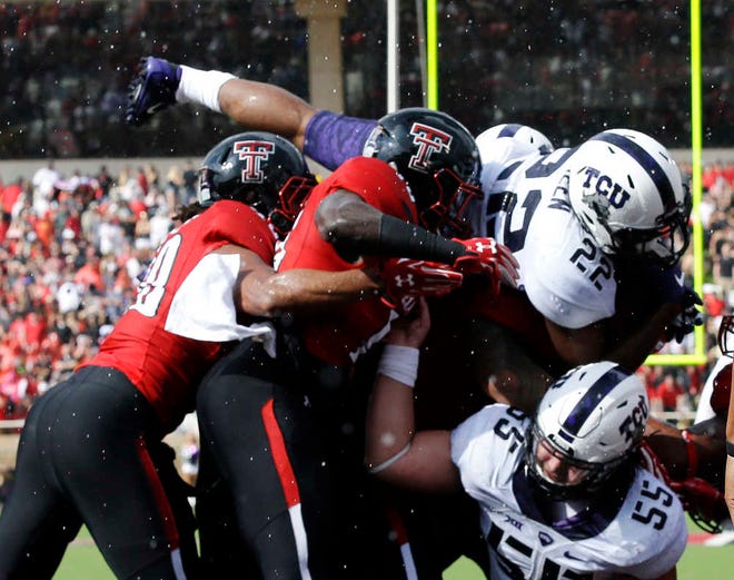 TCU running back Aaron Green (22) goes over the line with teammate center Joey Hunt (55) and Texas Tech defenders Dakota Allen (40) and Malik Jenkins to score a touchdown during the first half of an NCAA college football game Saturday, Sept. 26, 2015, in Lubbock, Texas. (AP Photo/LM Otero)