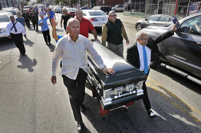 From the left, Juan Lopez, pastor of Christiana Iglesia La Hermonsa in Worcester, joins Julio Torres, Robert Mato and Jose Luis Perez, all of Worcester, as they wheel a casket down Main Street during an anti-violence procession Saturday in Worcester. T&G Staff/Paul Kapteyn