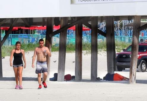 Joggers head out for a run as homeless people sleep under the Daytona Beach Pier and a Volusia County Beach Safety officer patrols nearby. The officers can roust homeless sleepers at night because of a no-camping ban, but daytime sleepers can stay if they aren't breaking laws. News-Journal/JIM TILLER