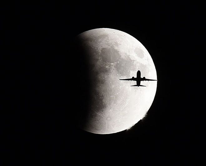A plane flies in front of the so-called supermoon during a lunar eclipse Sunday, Sept 27, 2015 in Geneva, Ill. It was the first time Sunday that the events have made a twin appearance since 1982, and they won't again until 2033 (Jeff Knox/Daily Herald via AP) MANDATORY CREDIT; MAGS OUT