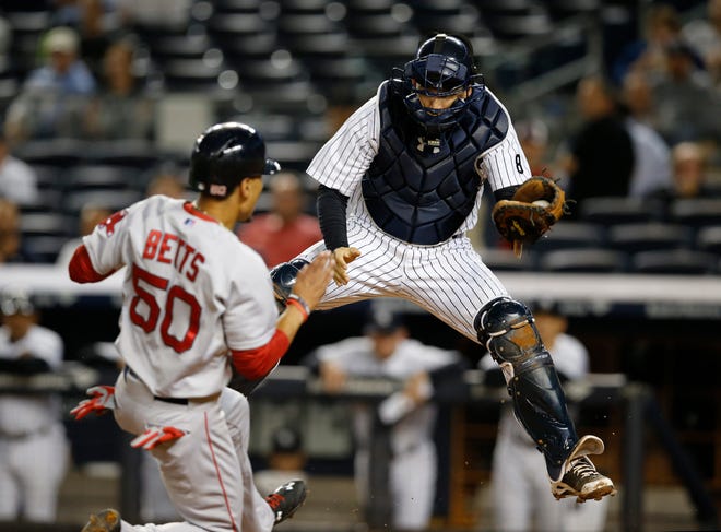 Red Sox's Mookie Betts (50) tries to score as Yankees catcher John Ryan Murphy drops to the plate after catching a high throw on a first-inning fielder's choice. Betts was out on the play at the plate. The Associated Press