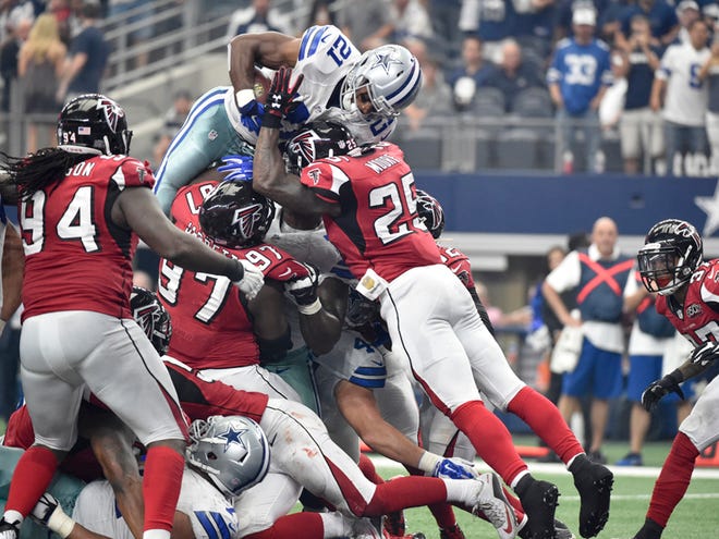 Dallas Cowboys running back Joseph Randle (21) leaps over Atlanta Falcons' Tyson Jackson (94), Grady Jarrett (97) and William Moore (25) as Ricardo Allen (37) watches for a touchdown in the first half of an NFL football game, Sunday, Sept. 27, 2015, in Arlington, Texas.