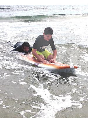 Somerset resident Conor Sullivan, 13 and autistic, gets a surfing lesson from Fall River's Chris Antao at South Shore Beach in Little Compton, R.I.