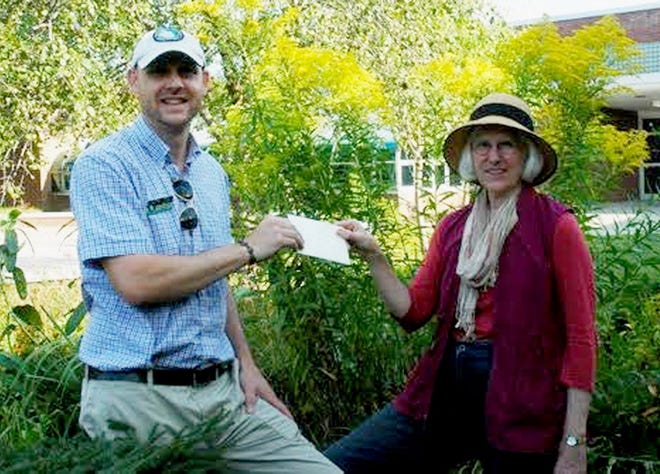 HAGC president Judith Oliver presents a $700 check to Simon Solomon, executive director of Friends of Rogers.