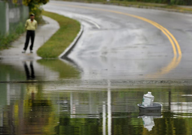 A pedestrian whose path was blocked by floodwaters Wednesday watches a plastic container under the railroad bridge on Southgate Street in Worcester. T&G Staff/Paul Kapteyn