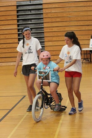 Volunteers Hanna Lydon, 15, of Scituate, left, and Sarah O’Donovan, 17, of Newton run alongside as Ava McLaughlin, 9, of Dorchester gains bike-riding skills in a program sponsored by CORSE at Scituate High School.