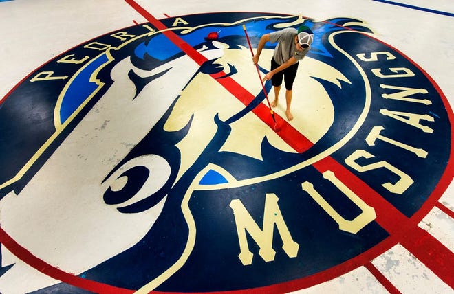 Owens Center employee Michael Damron works on painting a red stripe that runs through a painted Peoria Mustangs logo that will show through the hockey ice.