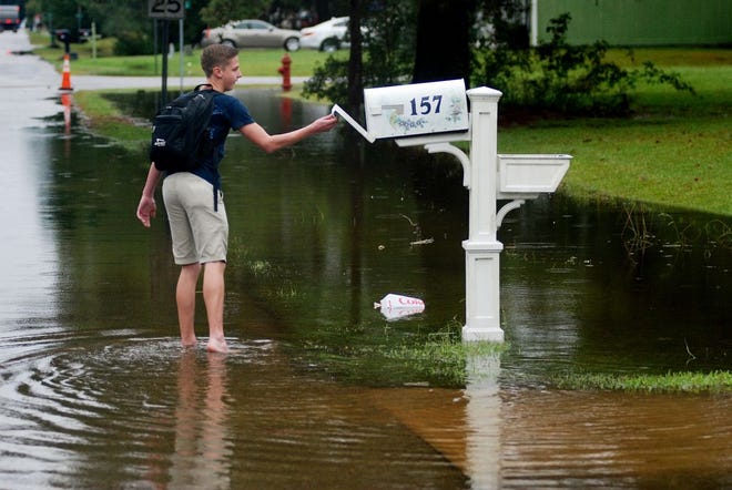 Michael Twiddy, 17, of Havelock, looks in his family's mailbox along a flooded section of Keith Drive near McCotter Boulevard on Friday in Havelock. Schools dismissed students early because of potential flooding issues.