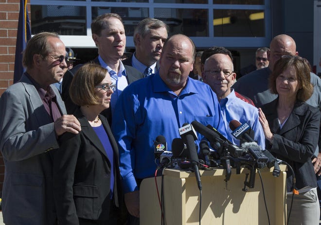 Officials from Oregon including Gov. Kate Brown (left), U.S. Senators Ron Wyden, Jeff Merkley and Congressman Peter DeFazio join members of the community of Roseburg including Douglas County Commisioner Tim Freeman (center) at a press conference in Roseburg Friday. (Chris Pietsch/The Register-Guard)